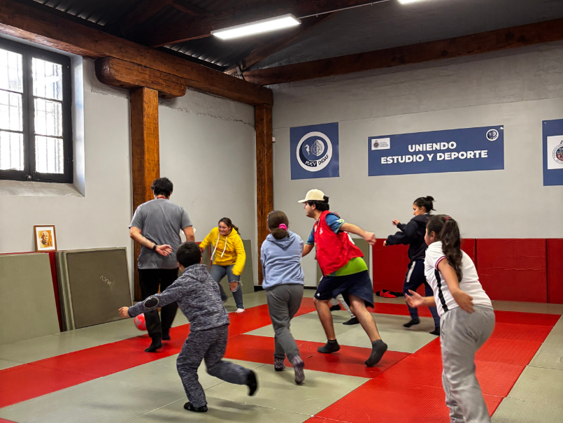 Niñas y niños junto a voluntarios Teletón, jugando con una pelota. 