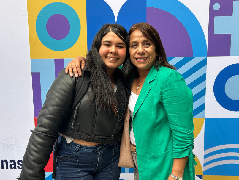 Estudiante junto a profesora posando en Casa Central PUCV; ambas sonríen. 